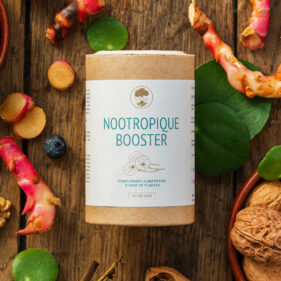 Flacon de complément alimentaire Nootropique Booster UNAE, 60 gélules, entouré de plantes, racines et noix sur fond en bois.