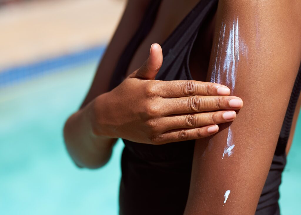 Application de crème solaire sur la peau, limitant la synthèse naturelle de vitamine D par exposition au soleil