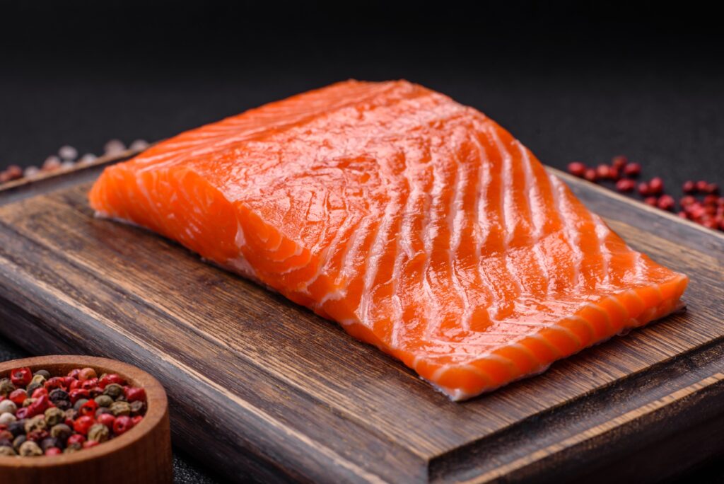 Filet de saumon cru, riche en vitamine D, sur une planche en bois