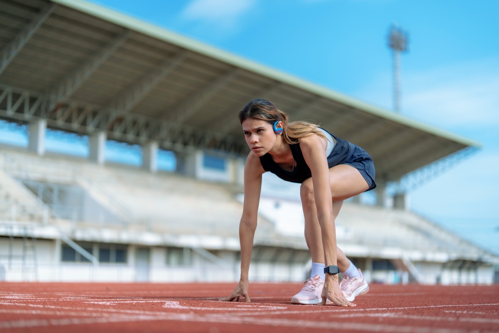 Femme sportive en position de départ sur une piste d’athlétisme, représentant l’augmentation des besoins en magnésium liée à l’activité physique