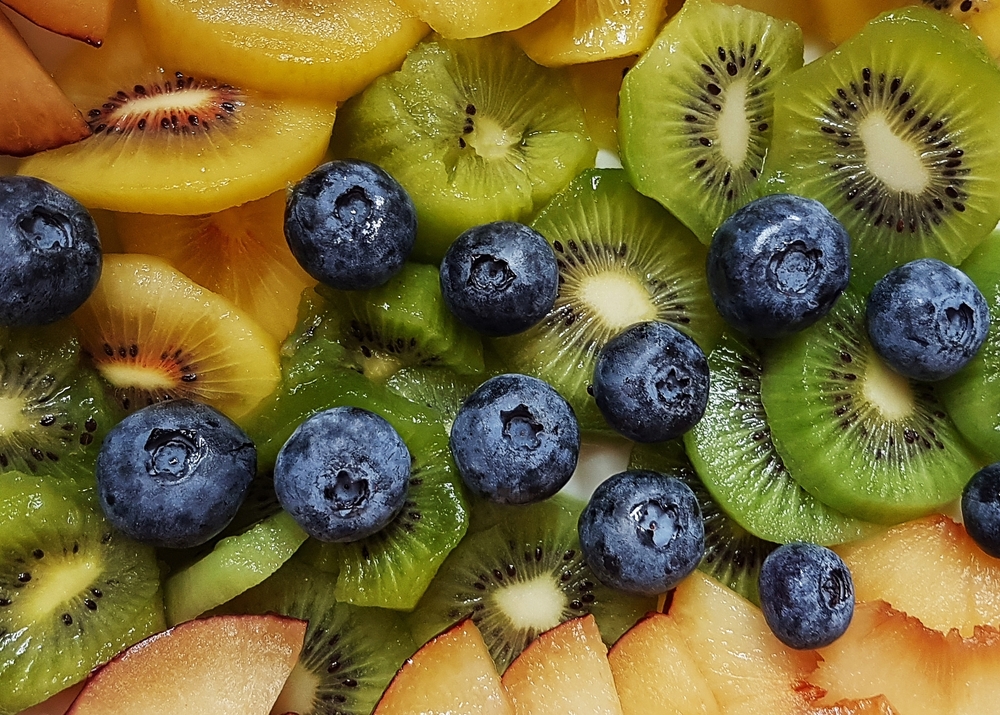 Assortiment de fruits riches en vitamine C, comme le kiwi et la myrtille, favorisant l’absorption du fer.