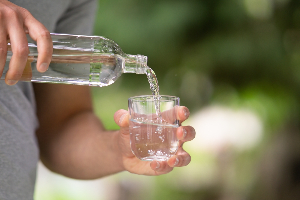 Photo d'une personne se servant un verre d'eau dans un verre, riche en magnésium, l'une des sources de magnésium liquides