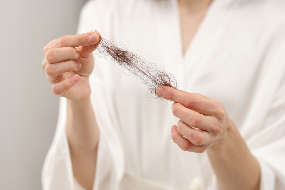 Femme tenant une poignée de cheveux tombés, illustrant une perte de cheveux soudaine liée à l’effluvium télogène.